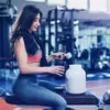 woman putting protein into a bottle at gym