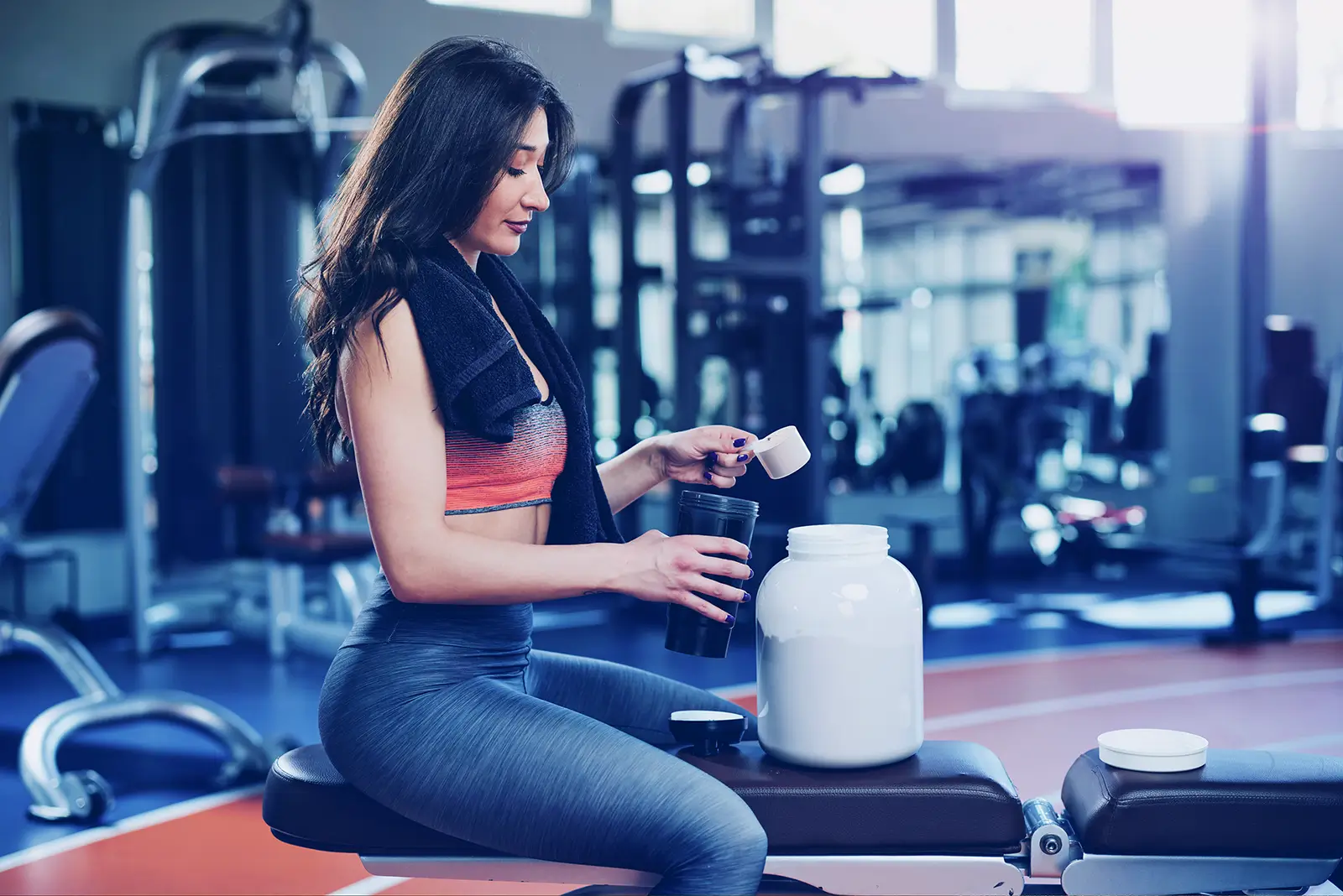woman putting protein into a bottle at gym