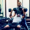 man doing incline barbell press with spotter