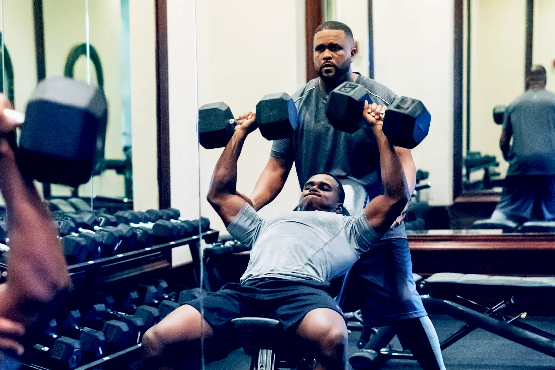 man doing incline barbell press with spotter