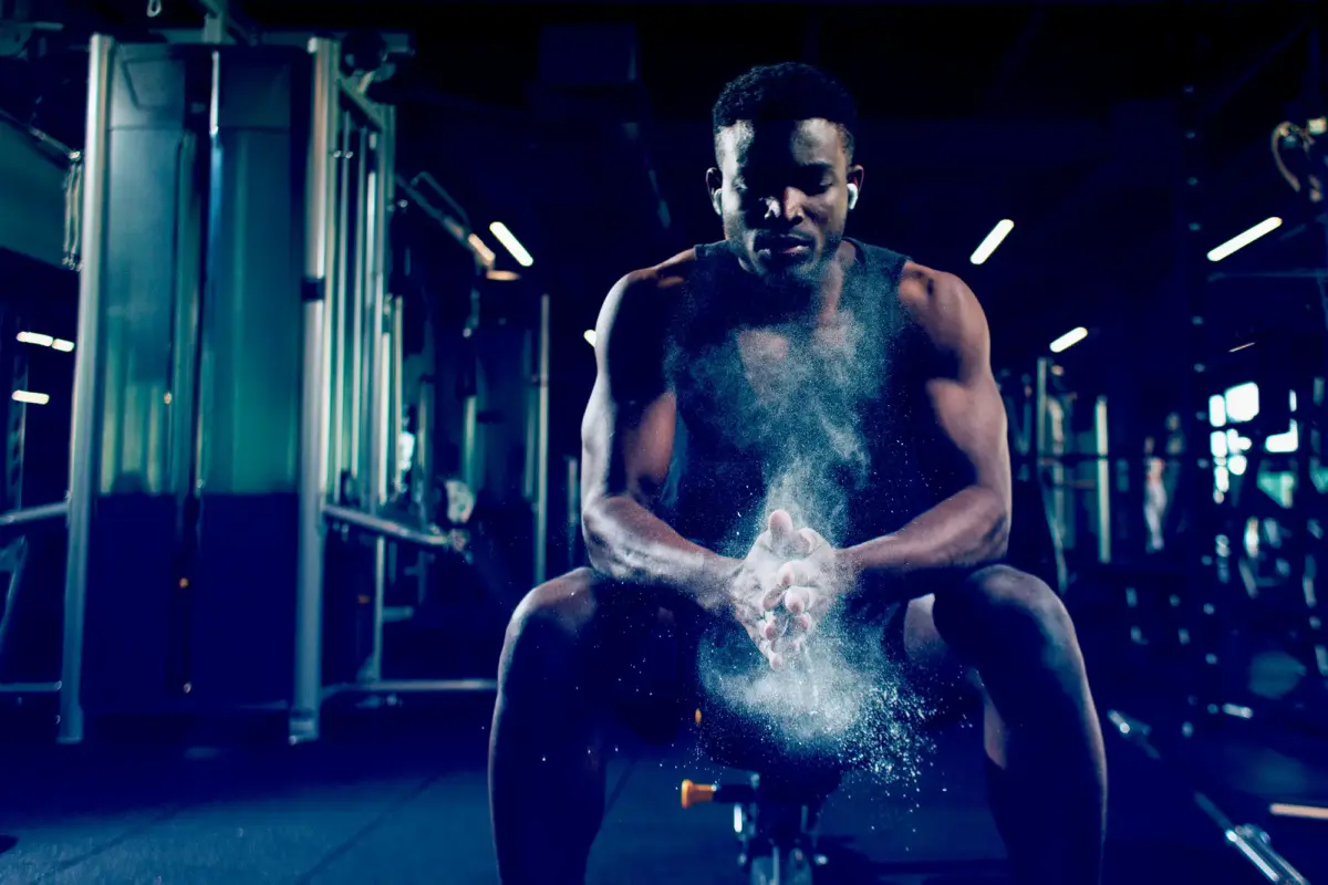 man clapping chalk hands at the gym